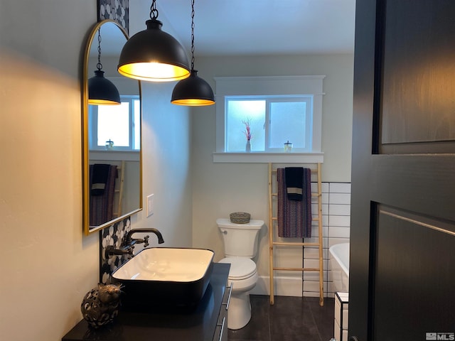 bathroom featuring a tub, vanity, and toilet