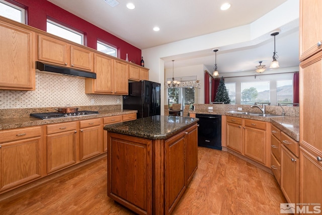 kitchen with black appliances, decorative light fixtures, sink, and light hardwood / wood-style flooring