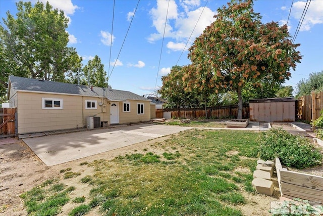 view of yard with central AC, a storage shed, and a patio area