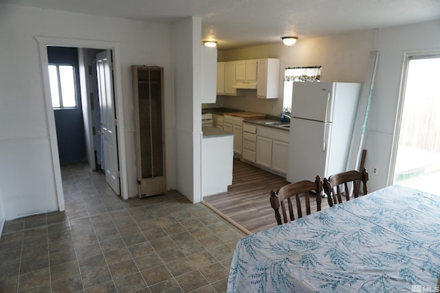 kitchen featuring sink, white refrigerator, white cabinetry, and dark hardwood / wood-style floors