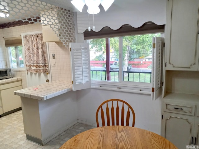 kitchen with ceiling fan and tile counters