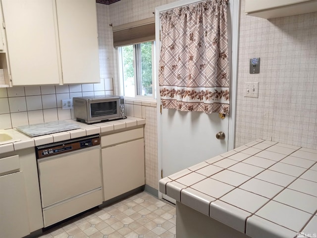 kitchen featuring dishwasher, white cabinets, decorative backsplash, and tile counters