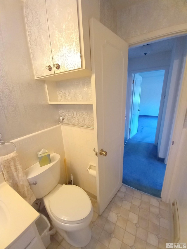 bathroom featuring toilet, vanity, tile walls, and tile patterned flooring