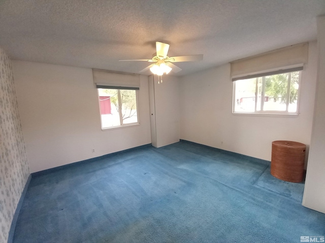 unfurnished room featuring dark colored carpet, a textured ceiling, and ceiling fan