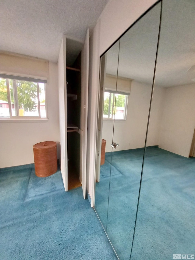 unfurnished bedroom featuring a textured ceiling, multiple windows, and carpet floors