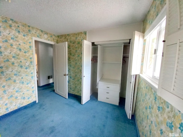 unfurnished bedroom with a textured ceiling, light colored carpet, and a closet