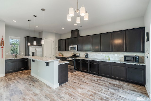 kitchen featuring decorative light fixtures, appliances with stainless steel finishes, a kitchen island, and light wood-type flooring