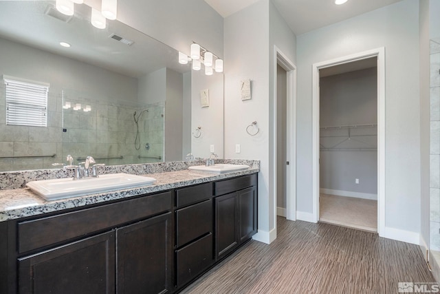 bathroom with tiled shower and vanity