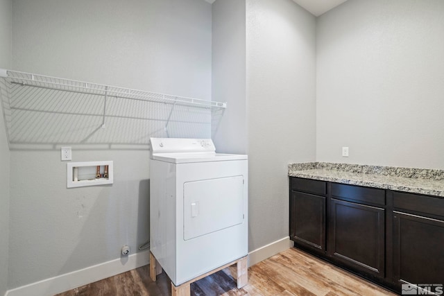 laundry area featuring washer / dryer, cabinets, and light hardwood / wood-style flooring