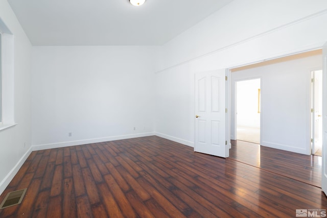 empty room featuring lofted ceiling and dark wood-type flooring