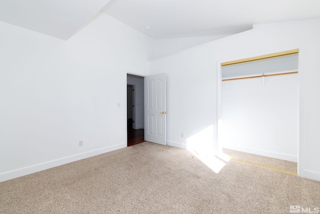unfurnished bedroom with a closet, carpet flooring, baseboards, and vaulted ceiling