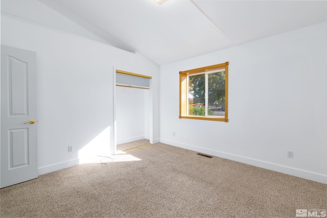 unfurnished bedroom featuring lofted ceiling, a closet, and carpet