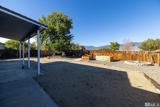 view of yard with a garden, a mountain view, a fenced backyard, and a patio area
