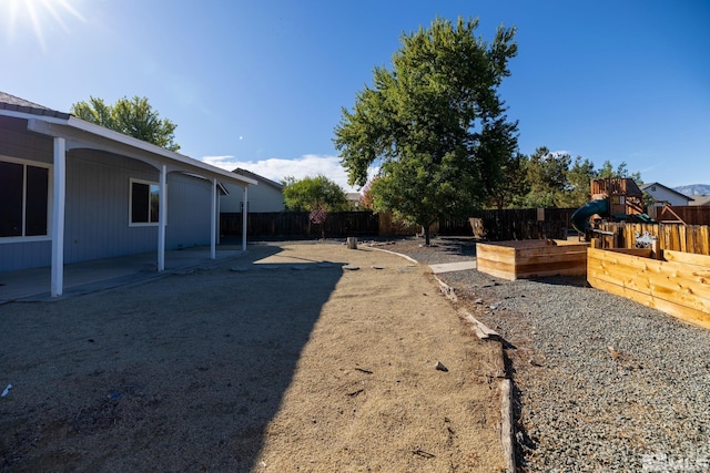 view of yard featuring a fenced backyard, a playground, and a patio