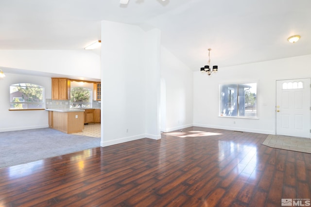 unfurnished living room featuring dark hardwood / wood-style floors, vaulted ceiling, and a chandelier