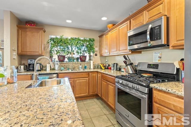 kitchen with sink, light stone counters, stainless steel appliances, and light tile patterned floors