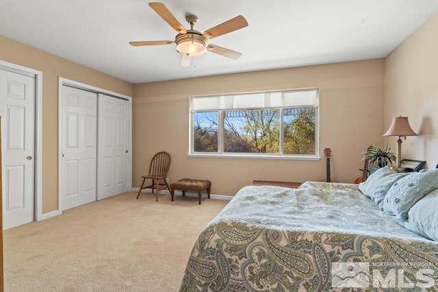 carpeted bedroom featuring ceiling fan and multiple closets