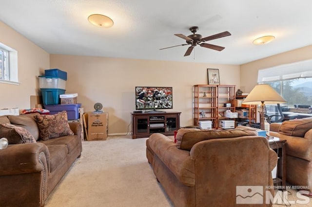 living room featuring ceiling fan, light carpet, and a wealth of natural light