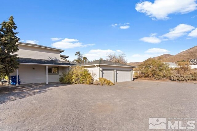 view of side of home with a mountain view and a garage