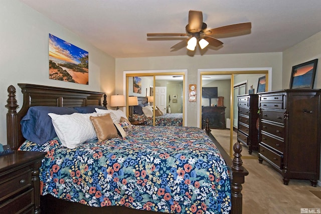 bedroom with ceiling fan, two closets, and light carpet