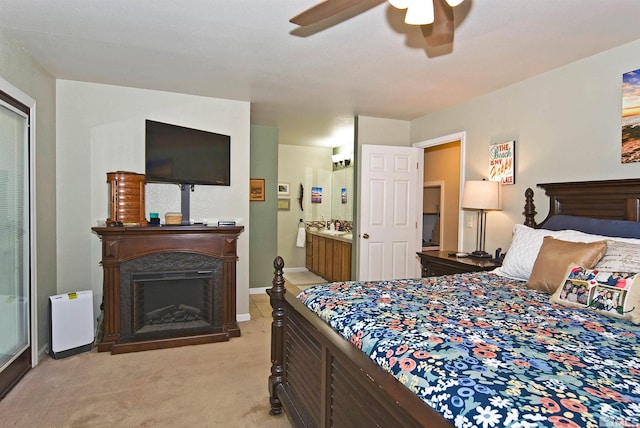 bedroom featuring ceiling fan, ensuite bath, and light carpet