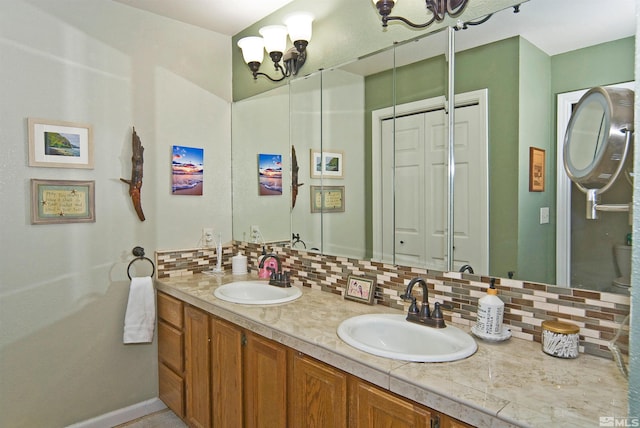 bathroom featuring vanity, an inviting chandelier, and backsplash