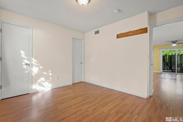 empty room with light wood-type flooring, ceiling fan, and a textured ceiling