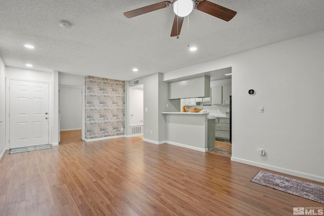 unfurnished living room featuring light wood-type flooring, ceiling fan, and a textured ceiling