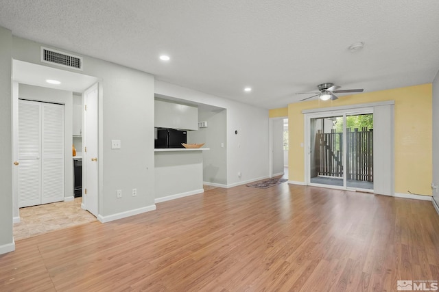 unfurnished living room with ceiling fan, light hardwood / wood-style floors, and a textured ceiling