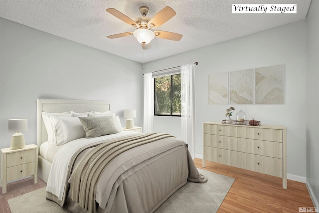 bedroom featuring ceiling fan, a textured ceiling, and light wood-type flooring