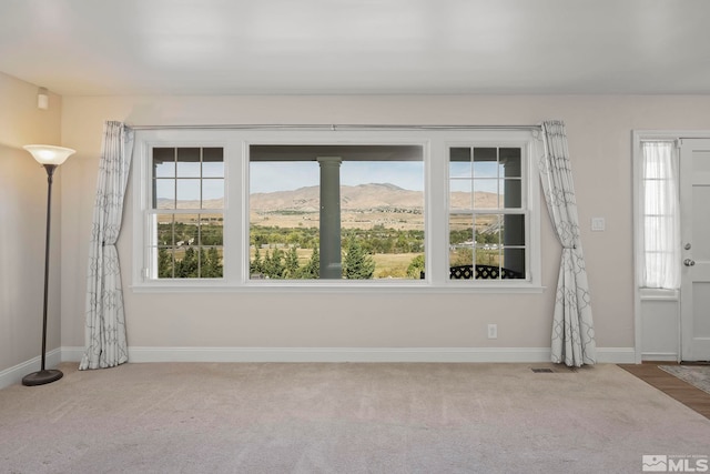 carpeted spare room with a mountain view and a healthy amount of sunlight