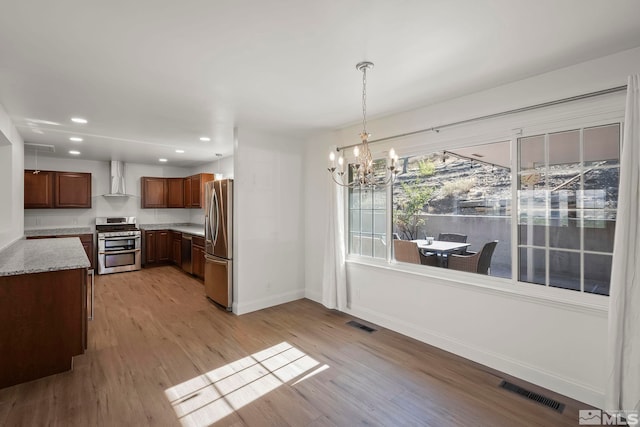 kitchen with light wood-type flooring, a notable chandelier, pendant lighting, and stainless steel appliances