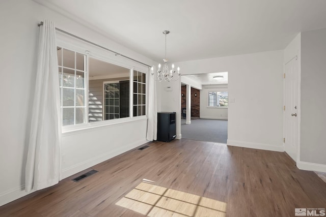 unfurnished dining area with wood-type flooring and a chandelier