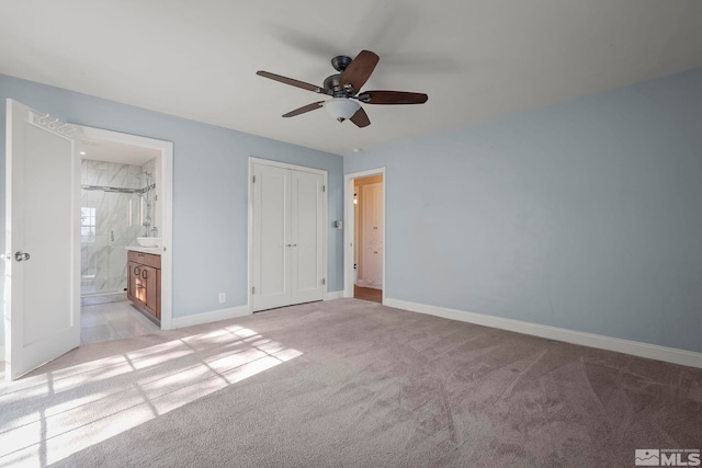 unfurnished bedroom with ceiling fan, a closet, connected bathroom, and light colored carpet