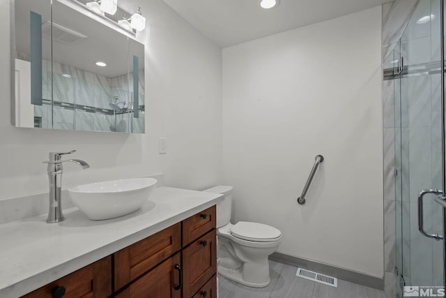 bathroom with vanity, a shower with shower door, and toilet