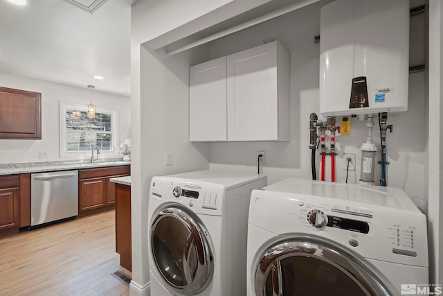 clothes washing area featuring light hardwood / wood-style flooring, separate washer and dryer, tankless water heater, and sink