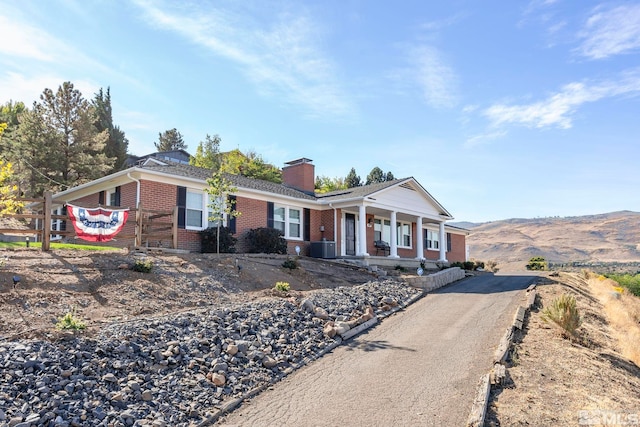 ranch-style home with a mountain view, covered porch, and central AC unit