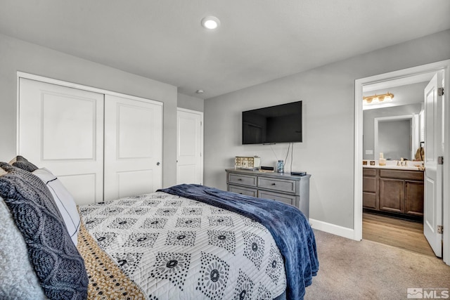 bedroom featuring light colored carpet, sink, a closet, and ensuite bathroom