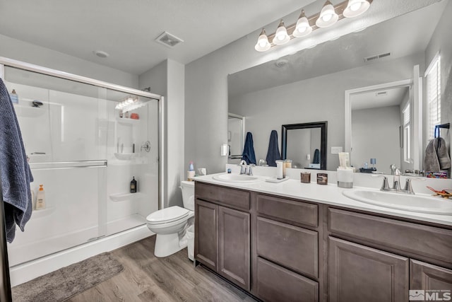 bathroom with hardwood / wood-style floors, vanity, toilet, and a shower with shower door