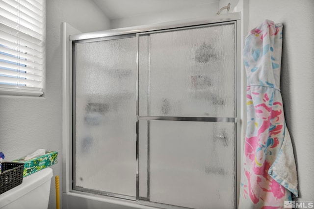 bathroom featuring toilet and a shower with door