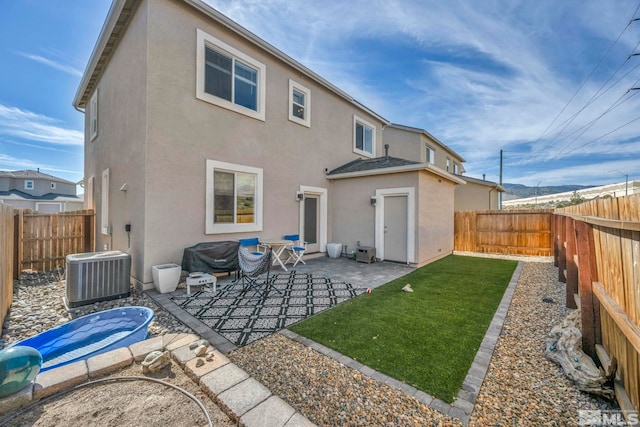 back of property with central AC unit and a patio