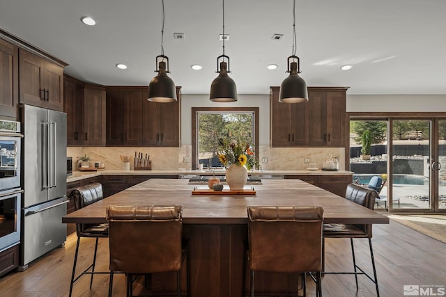 kitchen with stainless steel appliances, light hardwood / wood-style flooring, and a center island