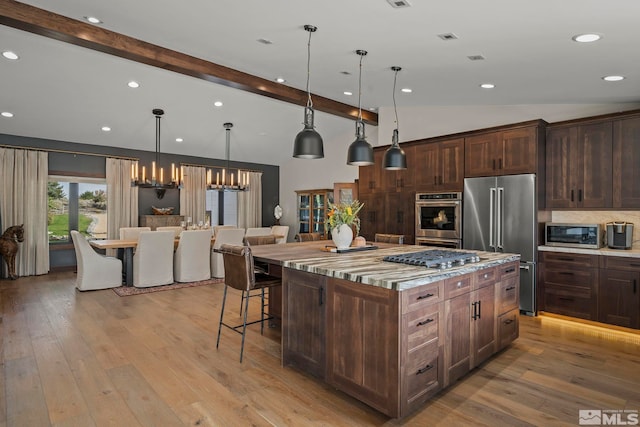 kitchen with a kitchen island, decorative light fixtures, a chandelier, appliances with stainless steel finishes, and lofted ceiling with beams