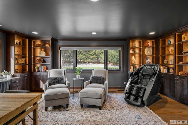 sitting room with ornamental molding and light hardwood / wood-style floors