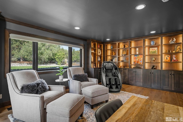 living area with ornamental molding and light hardwood / wood-style flooring