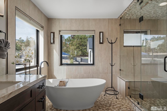 bathroom with vanity, tile walls, and separate shower and tub