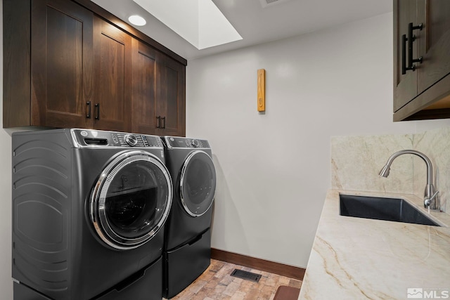 clothes washing area featuring washer and clothes dryer, sink, and cabinets