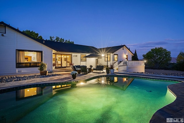 pool at dusk featuring french doors and a patio