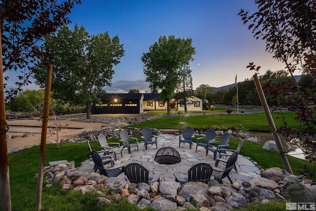 patio terrace at dusk with a fire pit and a lawn