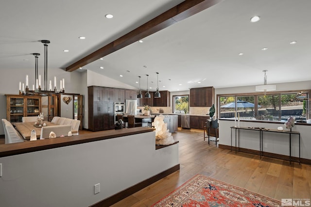 living room with vaulted ceiling with beams, a chandelier, and light hardwood / wood-style floors